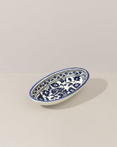 A single oval ceramic plate with a hand-painted blue and white floral design, displayed on a white background, highlighting its delicate craftsmanship.